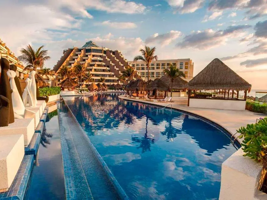 Alberca de un resort todo incluido frente al mar en Cancún al atardecer